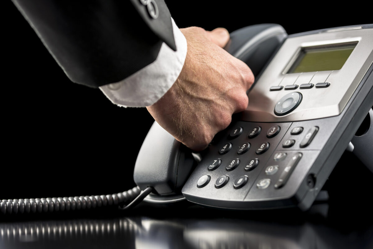 A businessman grabs his IVR phone and is about to answer a call.